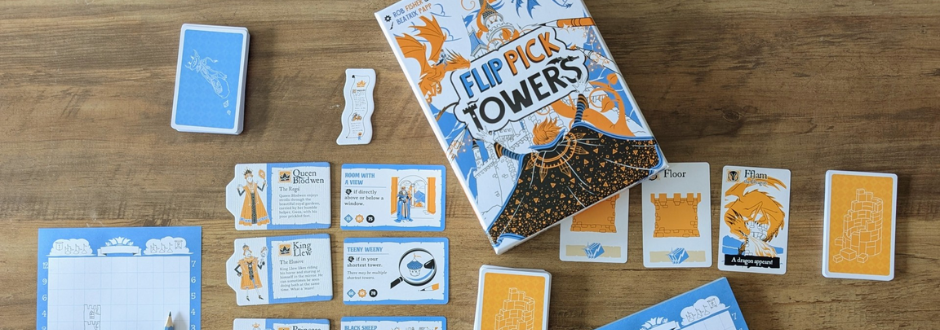 Box and cards of the game "Flip Pick Towers" are on a wooden table. The design is orange and blue, featuring castle and character illustrations.
