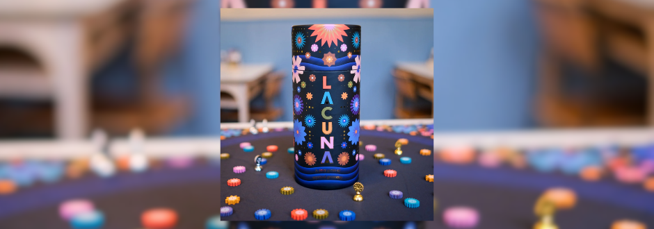 A vibrant cylindrical container labeled "Lacuna," adorned with colorful floral patterns, sits on a table surrounded by small, colorful tokens. The scene conveys a playful and artistic tone.