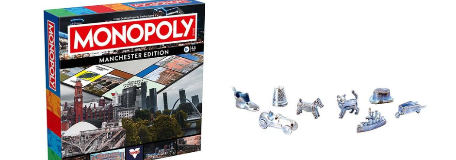 Monopoly Manchester Edition box with city landmarks, alongside silver game tokens including a shoe, car, dog, cat, ship, and hat.