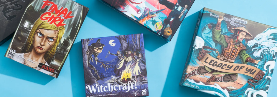 A trio of colourful board game boxes, Final Girl, Witchcraft!, and Legacy of Yu, displayed on a bright blue surface.