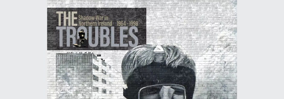 A monochrome mural-style image titled The Troubles: Shadow War in Northern Ireland 1964–1998, featuring a masked figure against a brick wall backdrop.