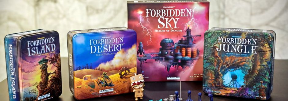 Four board game boxes are displayed: "Forbidden Island," "Forbidden Desert," "Forbidden Sky," and "Forbidden Jungle." A small toy character and game pieces are in front, creating an adventurous and playful atmosphere.