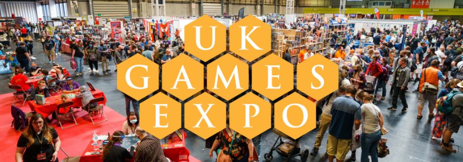 Crowded UK Games Expo with diverse attendees exploring exhibits and playing games. Bright, bustling atmosphere featuring a prominent hexagonal logo.